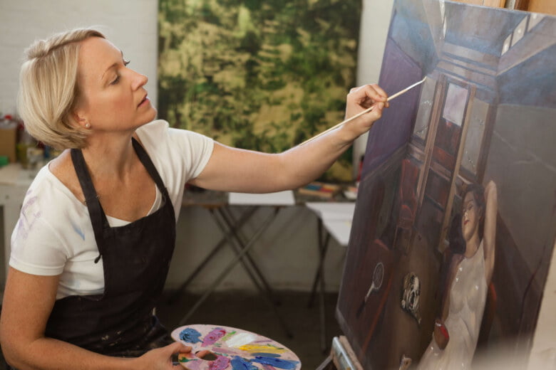 Kobieta tworząca obrazy na płótnie w studiu artystycznym.